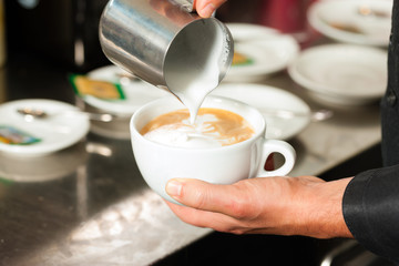 Barista bereitet Cappuccino zu in seinem Cafe