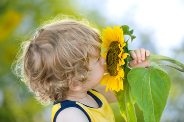 Kind mit Sonnenblume auf sonnig-grünem Hintergrund