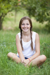 Beautiful teen girl in the park at green grass.