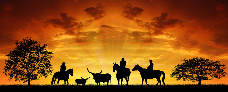 Silhouette cowboys with horses in the sunse