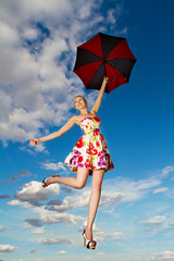 Flying girl with umbrella in the blue blue sky
