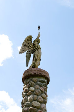 Angel hold torch on stone platform sky background