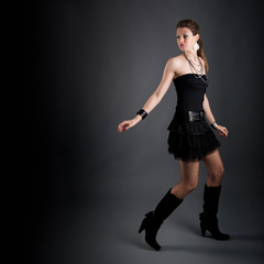 Beautiful girl with black dress against dark background escaping