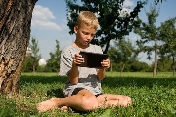 Naklejka na ściany i meble Boy playing in the tablet PC
