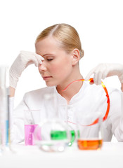 Tired doctor is surrounded with medical glassware, isolated