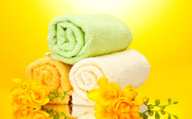 Obraz na płótnie Canvas colorful towels and flowers on yellow background