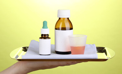Hand holding tray with medicines on green background