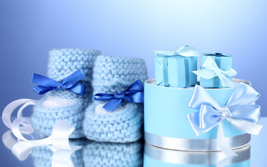 beautiful gifts and baby's bootees on blue background