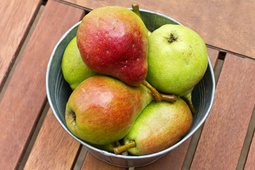 Fresh colourful pears in vintage metallic bowl on wooden backgro