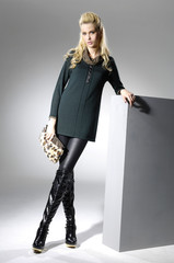 Full length fashionable woman hold purse posing near the cube