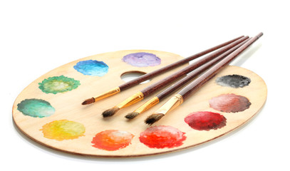 wooden art palette with paint and brushes isolated on white