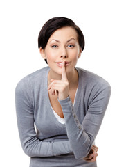 Woman shows silence gesture touching her lips, isolated on white