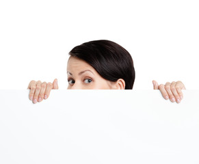 Woman hides behind a huge sheet of white cardboard, isolated