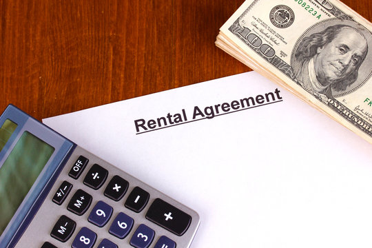 Rental agreement with dollars on wooden background close-up