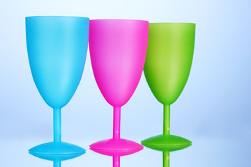 Bright plastic goblets on blue background