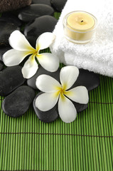 Fototapeta na wymiar frangipani flower and zen stones with candle on towel on mat