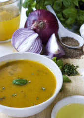 Bowl of yellow squash soup, cooking ingredients in background