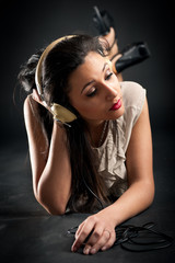 Beautiful girl listening to music against dark background.