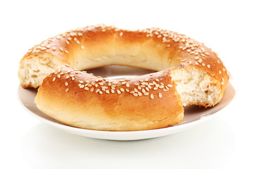 Bitten bagel with sesame seeds on plate isolated on white