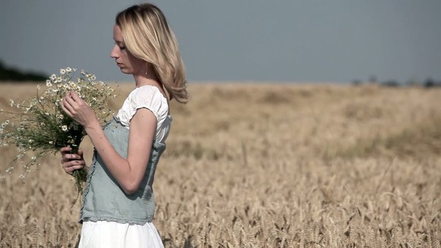 Frau mit Blumenstrauss im Kornfeld