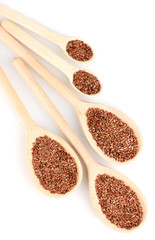 flax seeds in wooden spoons on white background close-up