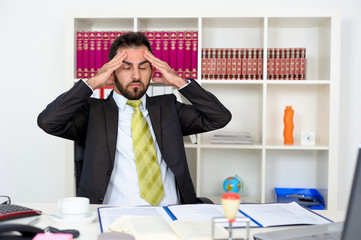 Geschäftsmann im Büro mit Kopfschmerzen