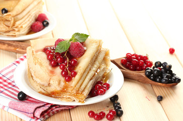 Delicious pancakes with berries, jam and honey on wooden table