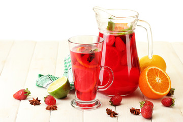 sangria in jar and glass with fruits, on white wooden table