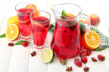 sangria in jar and glasses with fruits, on white wooden table