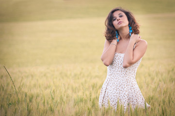Young beautiful woman in a wheat field with white dress.
