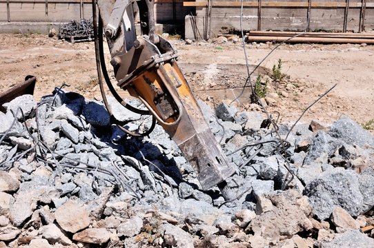 Escavatore con martellone demolisce struttura in cemento armato