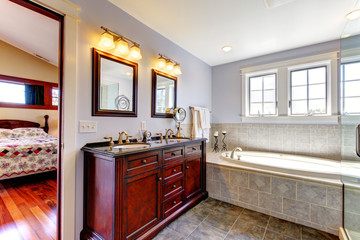 Nice lavendar bathroom with tub and wood cabinet with two sinks.