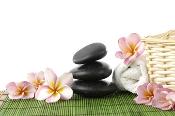 frangipani and zen stones and towel and wicker basket on mat