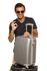 Male in sunglasses with silver travel suitcase showing OK
