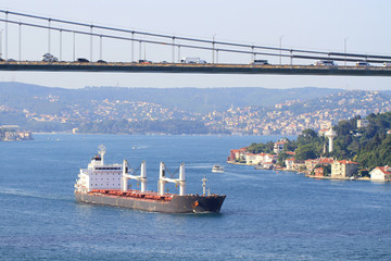Transportation with a cargo ship sailing under the bridge..