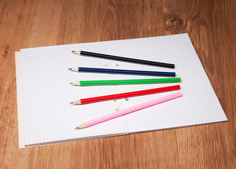 pencils and notebook on wooden table