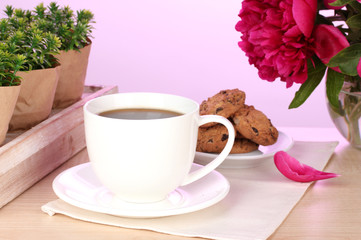 cup of coffee, cookies and flowers on table in cafe