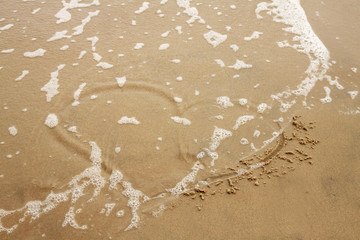 Heart on the beach washed away by waves