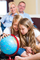 Family at home, the children playing with a globe