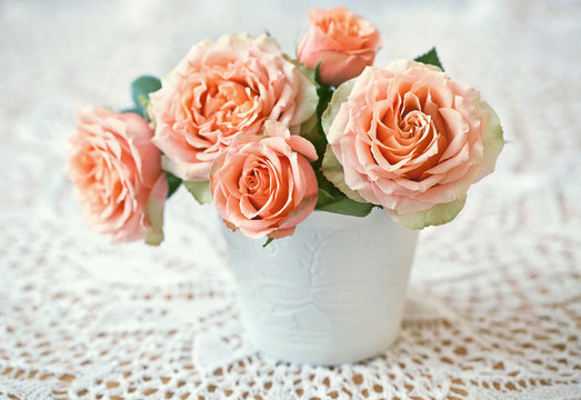 Beautiful fresh roses in a ceramic vase on a table.