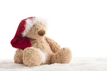 Teddy bear with xmas hat seated in the snow