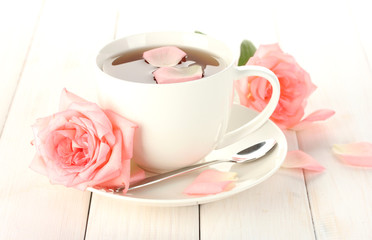 cup of tea with roses on white wooden table