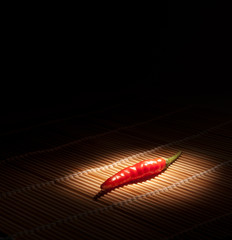 Hot chilli pepper floating over black background