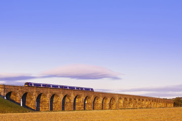 Old masonry arched viaduct carrying a train