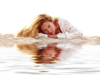 Junge Frau liegt im Sand mit Wasserspiegelung