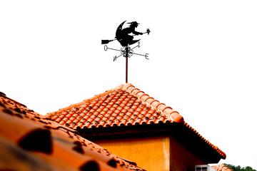 An isolated witch form wind vane  on orange roof