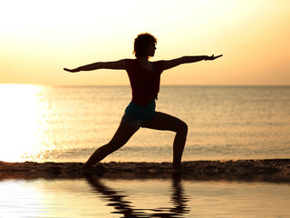 Frau macht Yoga am Strand Krieger Position mit Spiegelung