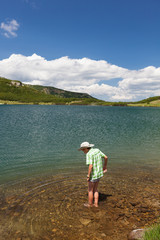 Fototapeta na wymiar Child with hat, barefoot in a lake
