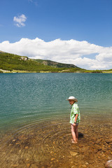 Fototapeta na wymiar Child with hat, barefoot in a lake