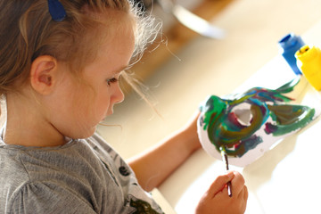 Little girl painting a carnival mask